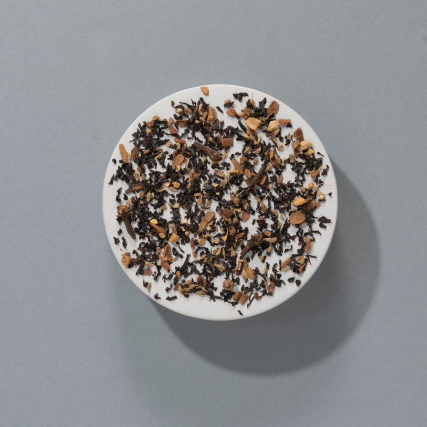 Loose Indian Spiced Chai, black tea with pieces of cinnamon and ginger, on a round white dish